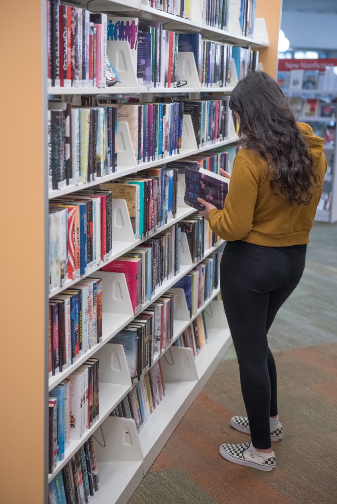 Student browsing the library's stacks of books. © steven e gross